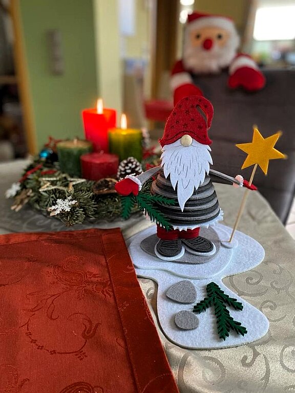 Der selbst gebastelte Weihnachtsmann aus Filz mit roter Mütze, weißem Baart und einem Stern in der Hand